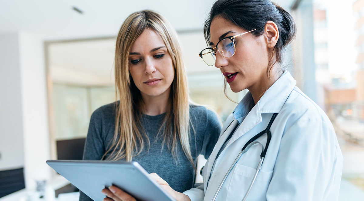 Eine Ärztin erklärt einer Patientin einen Befund am Tablet-PC  