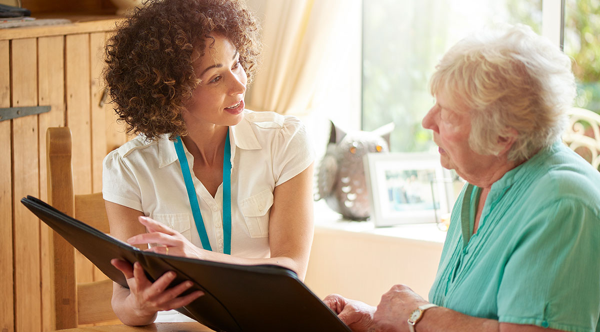 Eine Pflegekraft erklärt einer Seniorin etwas