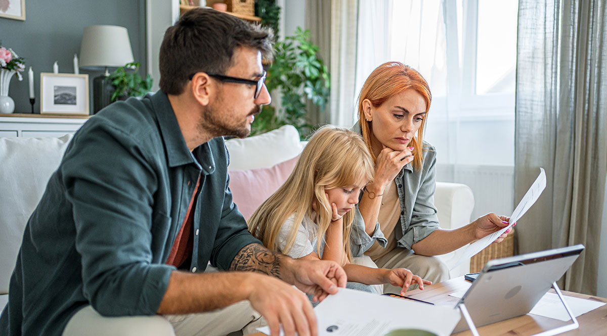 Eine Familie sitzt auf dem Sofa und studiert Unterlagen