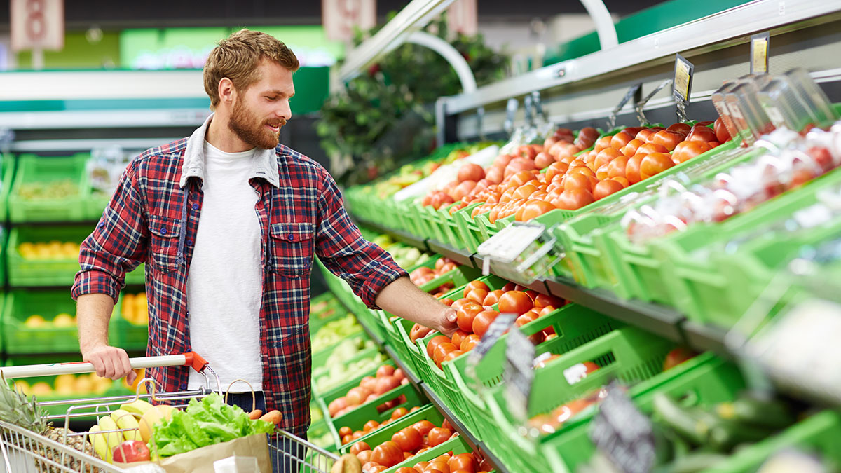Mann beim Einkaufen am Gemüseregal im Supermarkt