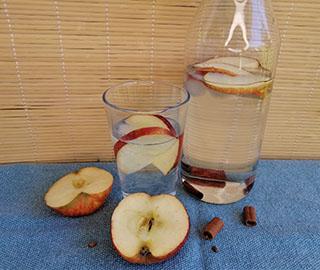 Apfel-Zimt-Wasser in einer Karaffe, Obst- und Gewürzdekoration