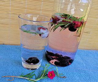 Wasserkaraffe mit Beeren und Rosmarinzweigen