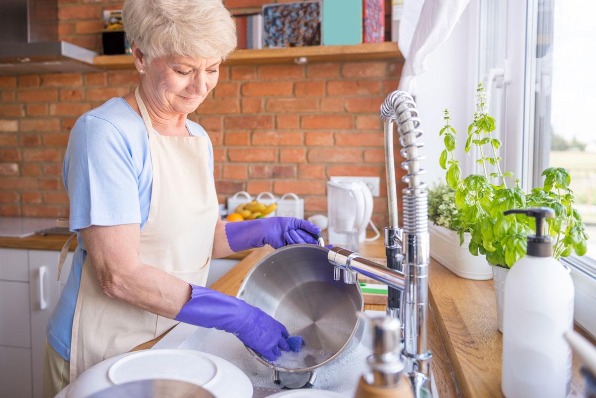 Eine Frau spült Töpfe in einem Spülbecken