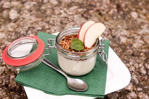 Ein Glas mit Joghurt, Müsli und Apfelscheiben