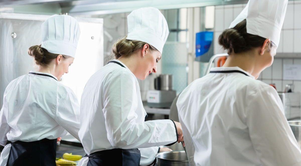 Drei Köchinnen bereiten in einer Großküche Essen zu
