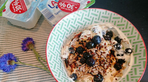 Ein Teller mit Quark-Müsli und Früchten, preisreduzierte Quarkpackungen mit Kurzem Mindesthaltbarkeitsdatum