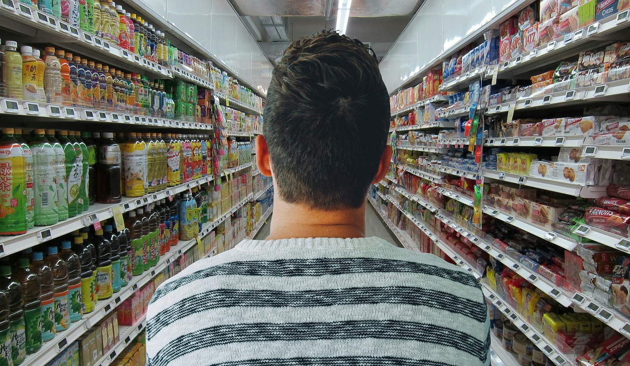 Junger Mann im Supermarkt zwischen Regalen