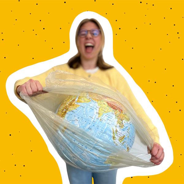 Eine junge Frau befreit eine in Plastikfolie eingepackte Erdkugel