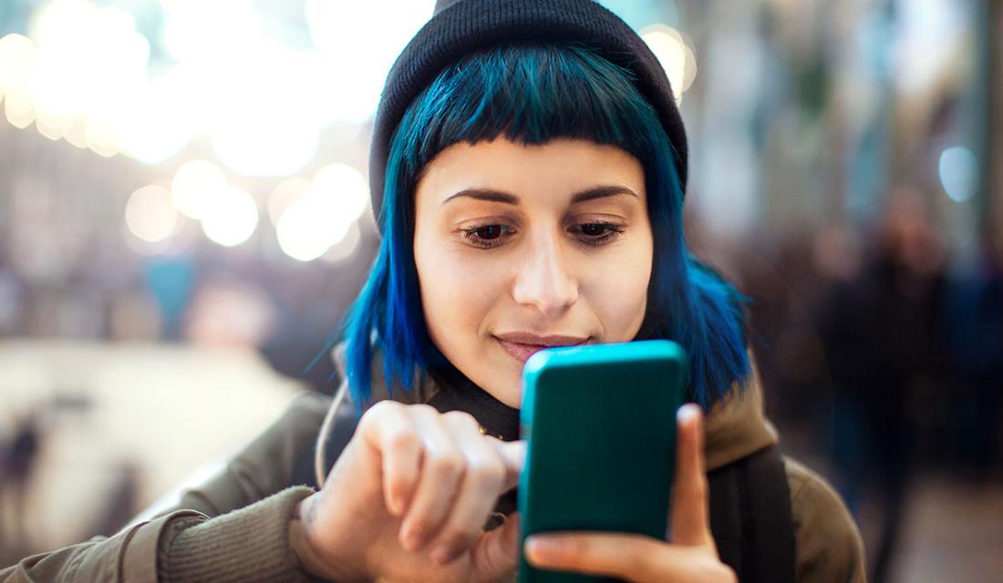 Eine junge Frau mit blauen Haaren macht ein Selfie von sich
