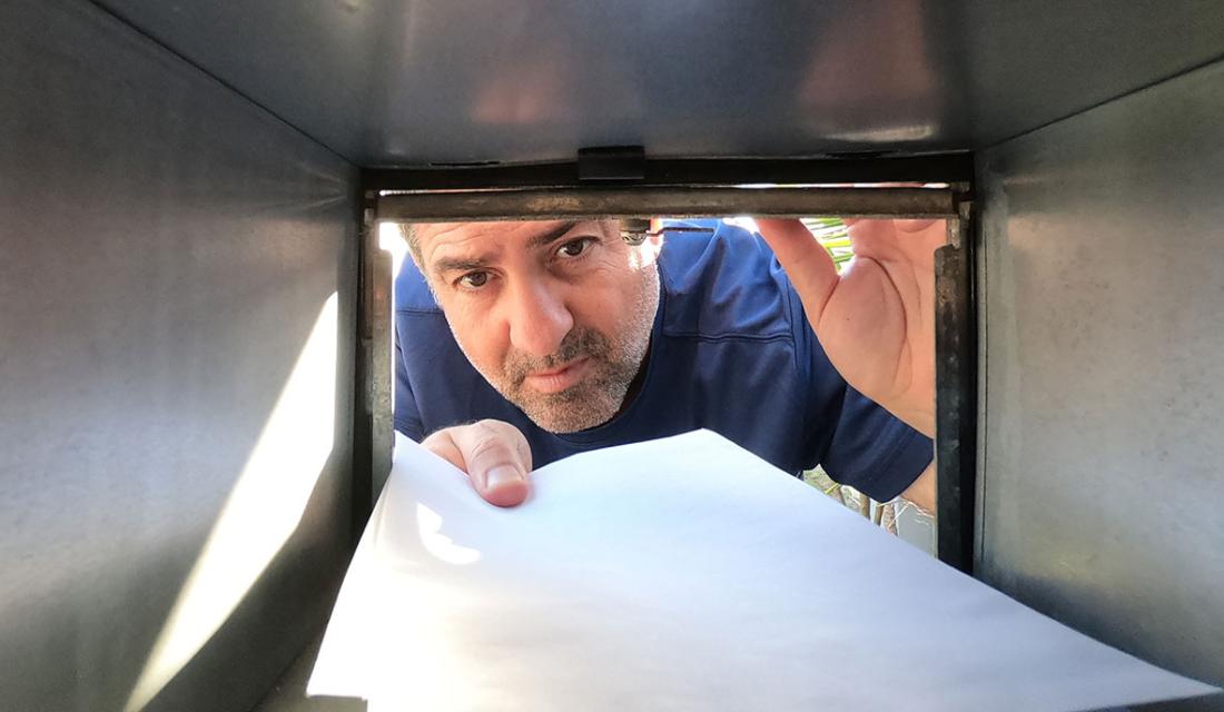 Betrügerische "Mahnung": Ein Mann holt einen Umschlag aus seinem Briefkasten