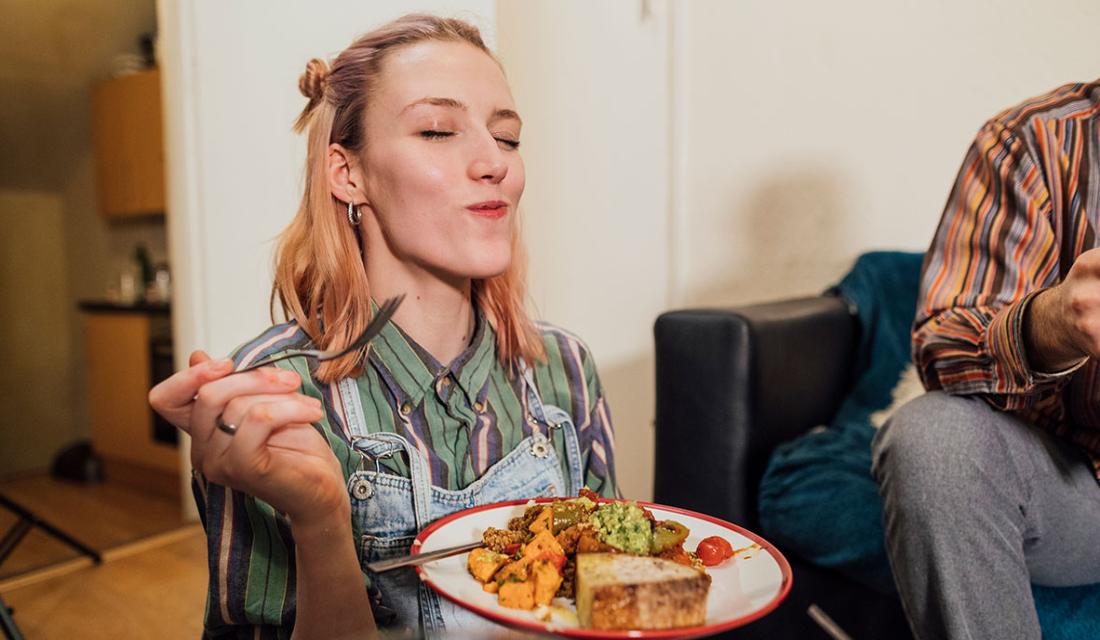 Eine junge Frau schließt beim Essen genießerisch die Augen