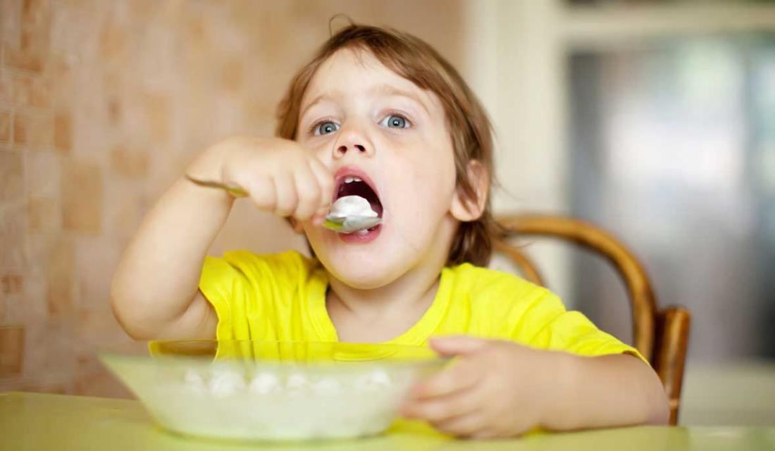 Ein Kind ist mit einem Löffel Quark aus einem teller