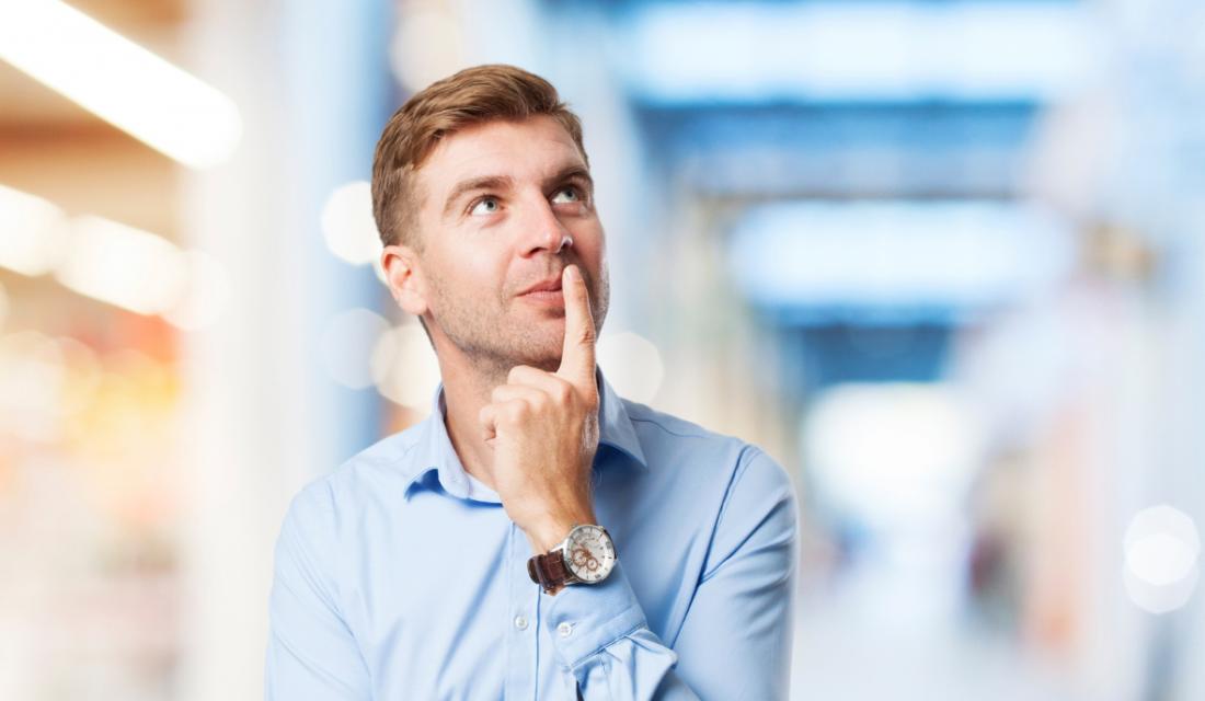 Ein junger Mann in hellblauem Hemd legt nachdenklich einen Finger an den Mund
