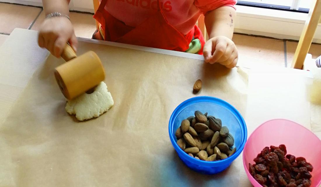 Kinderhände rollen mit einem kleinen Teigroller Hefeteig für Weckmänner 
