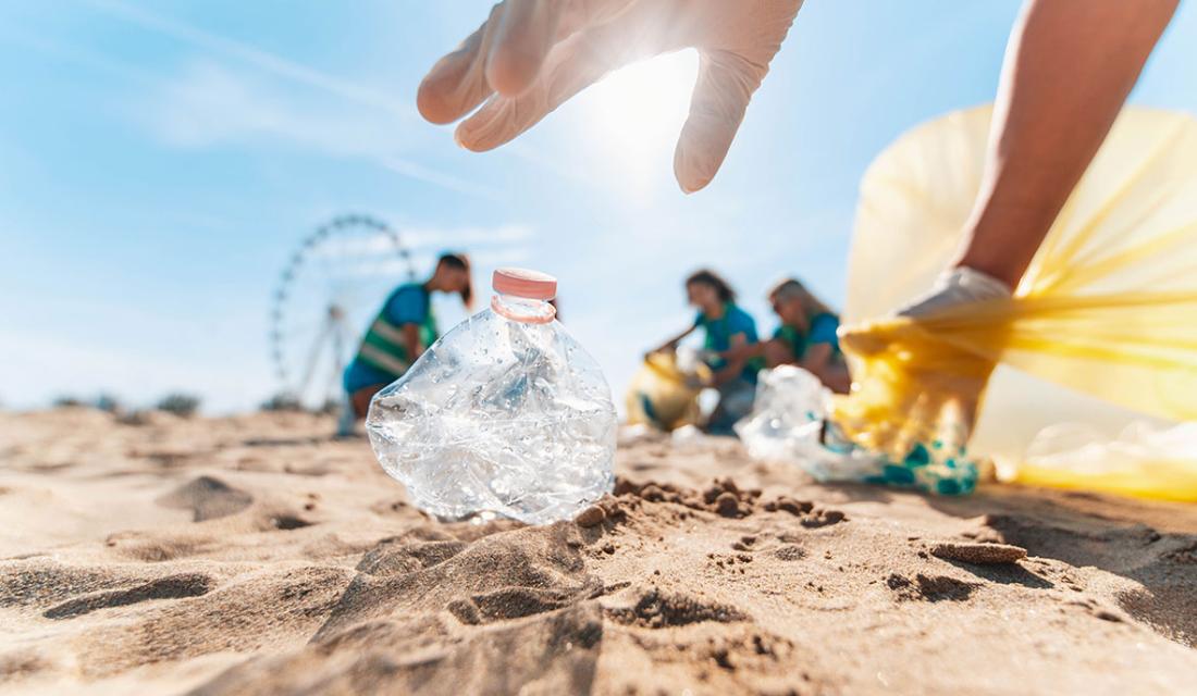 Ein Gruppe junger Menschen sammelt am Strand Plastikmüll ein