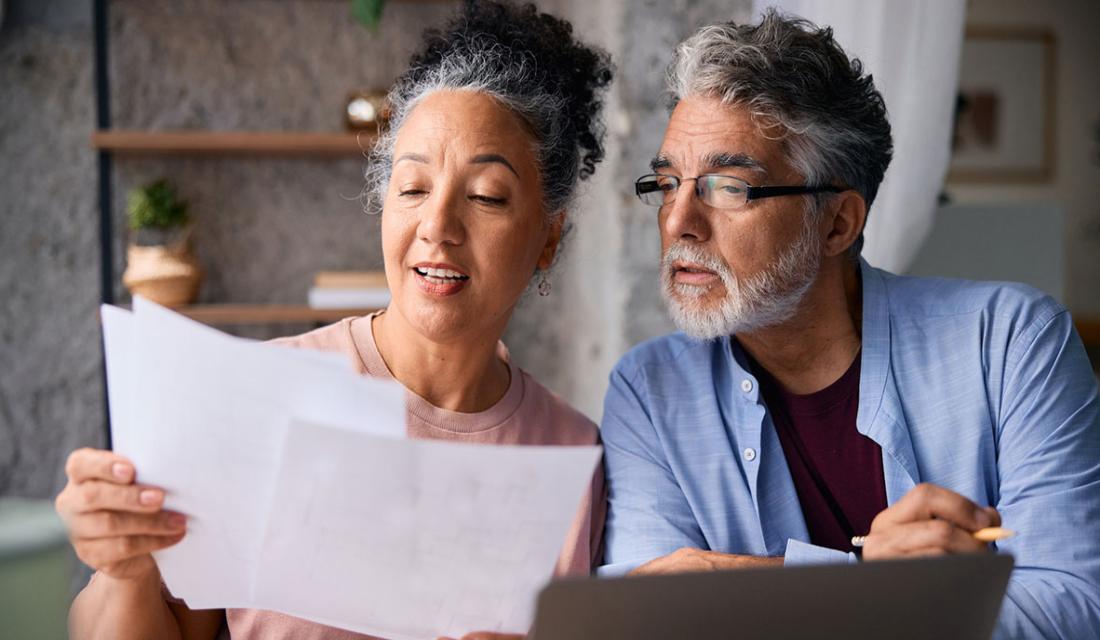 Ein Mann und eine Frau mittleren Alters schauen gemeinsam auf Unterlagen