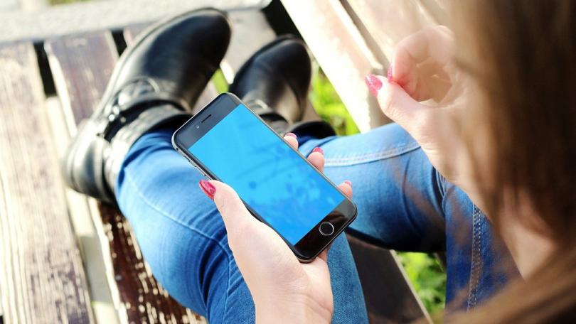 Frau auf Parkbank hält Smartphone in der Hand