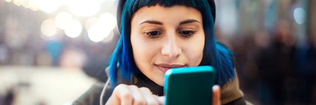 Eine junge Frau mit blauen Haaren macht ein Selfie von sich