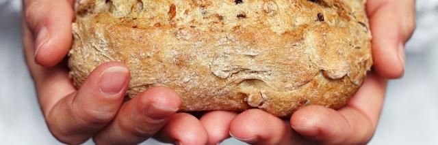 Jemand hält ein kleines Brot in beiden Händen