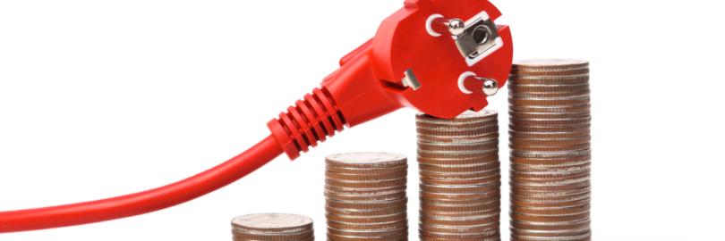 Ein Stromkabel liegt über mehreren, ansteigenden Münzhaufen.