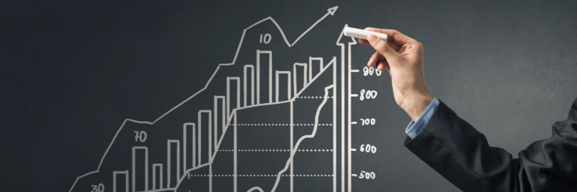 Jemand zeichnet mit Kreide eine Kursentwicklung auf eine Tafel