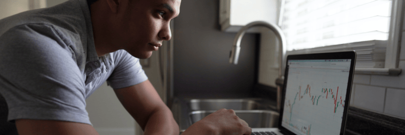 Junger Mann am Schreibtisch schaut auf Laptop-Bildschirm