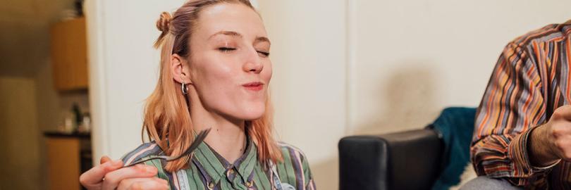 Eine junge Frau schließt beim Essen genießerisch die Augen