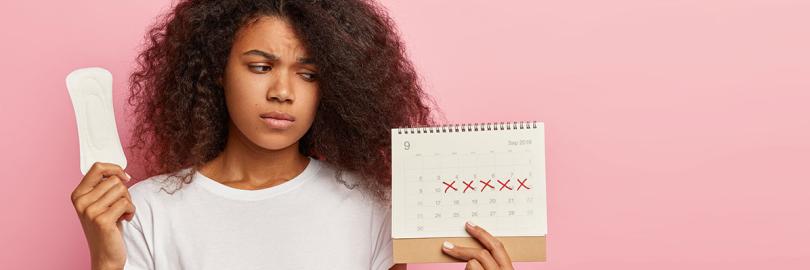 Eine Frau hält eine Slipeinlage und einen Kalender in der Hand, auf dem fünf Tage mit einem rotem Kreuz markiert sind