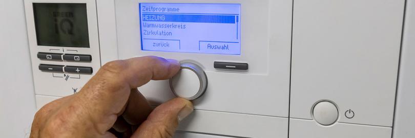 Jemand stellt die Temperatur an einer Heiztherme ein