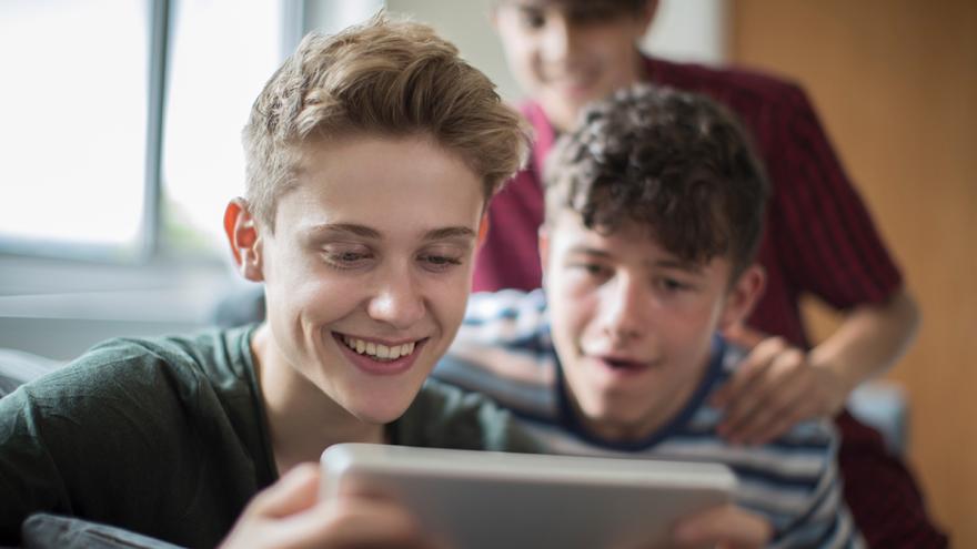 Drei Jugendliche spielen auf einem Smartphone
