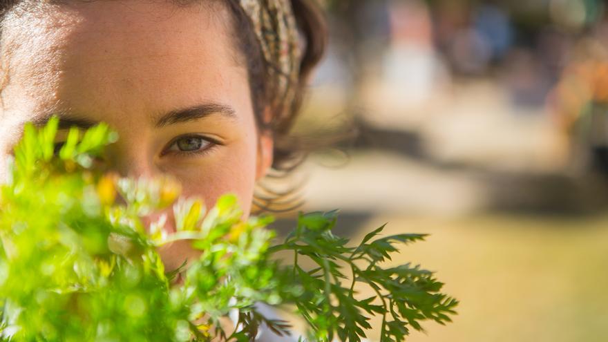 Junge Frau in Nahaufnahme, hält Pflanzen vor ihr Gesicht