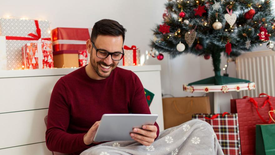 Junger Mann mit Tablet-PC kauft online Weihnachtsgeschenke