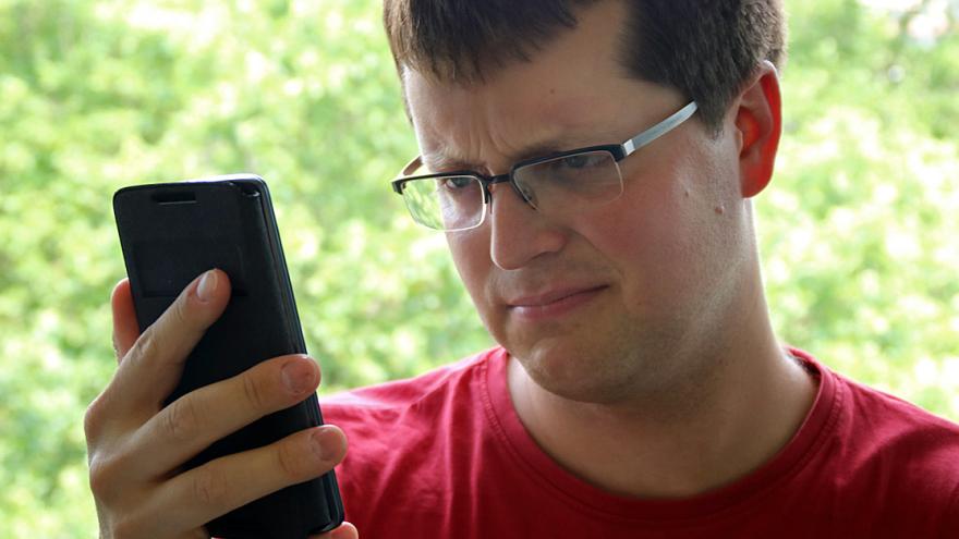 Mann schaut befremdet auf Smartphone