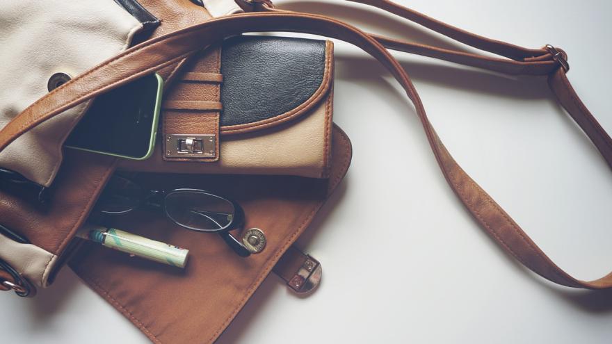 geöffnete Handtasche mit Portemonnaie, Stift und Brille