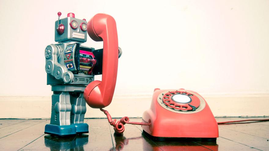 Spielzeug-Roboter telefoniert mit einem Wählscheibentelefon 
