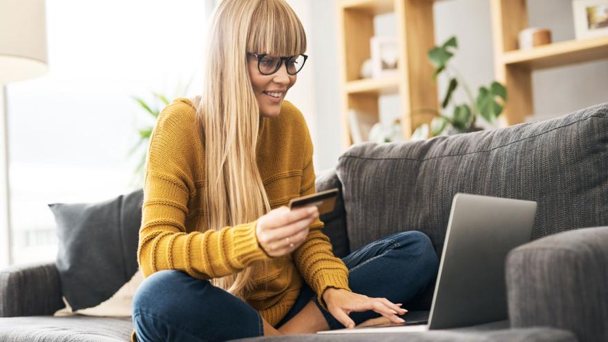 Frau auf dem Sofa mit Laptop und Kreditkarte beim Online-Shopping