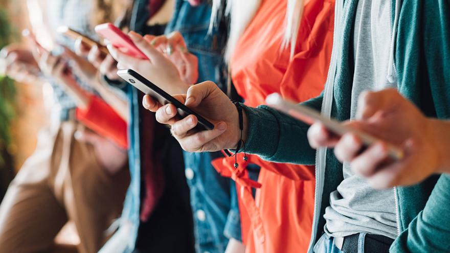 Nahaufnahme einer Gruppe Menschen, alle mit Smartphones in der Hand 