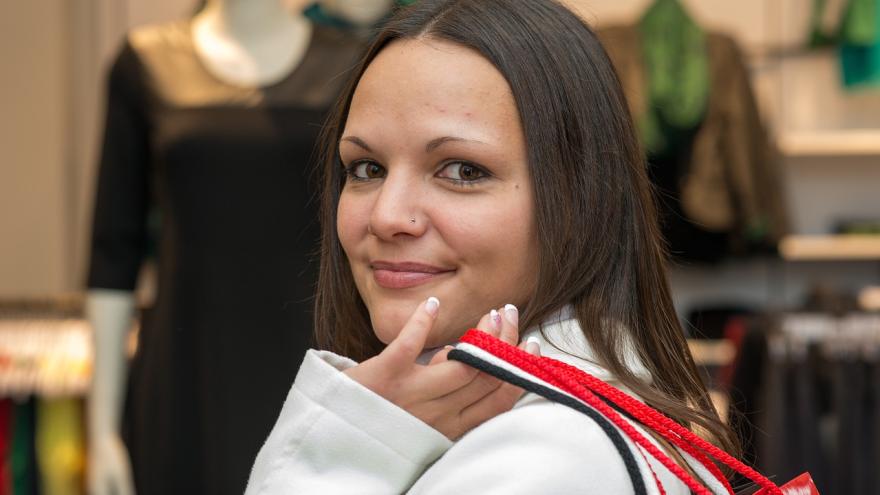 Junge Frau beim Shopping, trägt mehrere Tüten über der Schulter 