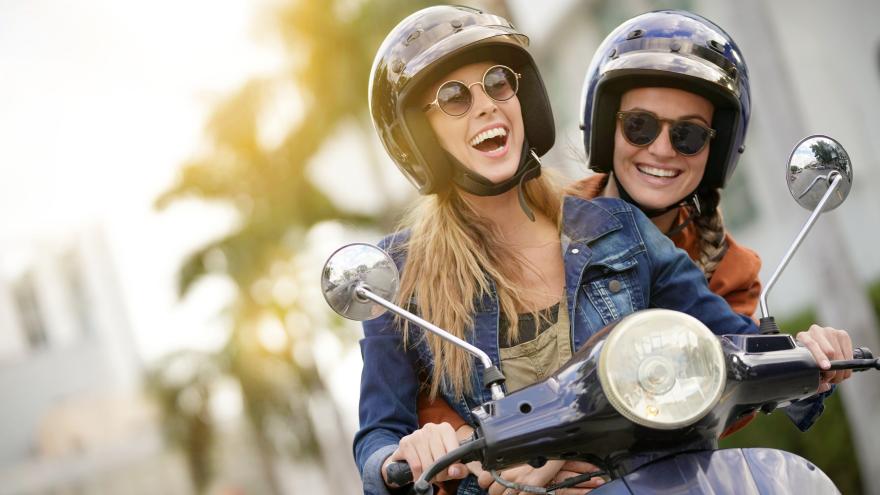 Zwei Frauen lachen auf dem Roller