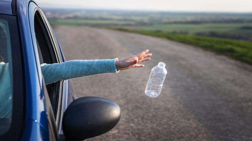 Jemand wirft eine Plastik-Trinkflasche aus dem Autofenster