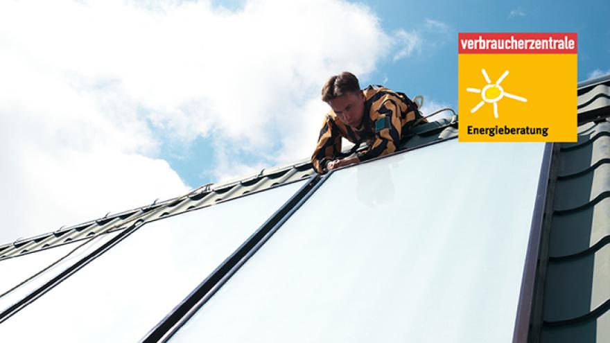 Jemand montiert große Solarpaneele auf einem Dach