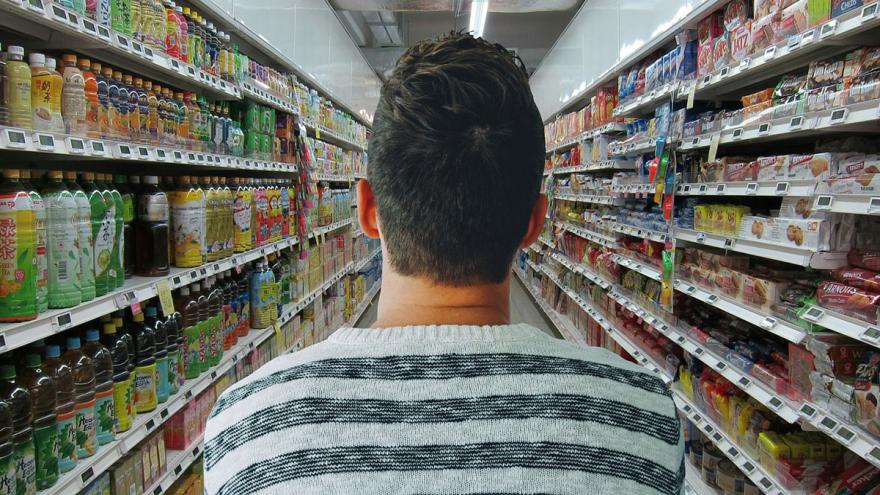 Einkaufsfalle Supermarkt: Ein Mann schiebt den Einkaufswagen durch einen Supermarktgang   