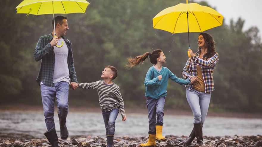 Versicherungen für unterschiedliche Lebenslagen: Erwachsene und Kinder laufen im regen unter Regenschirmen 