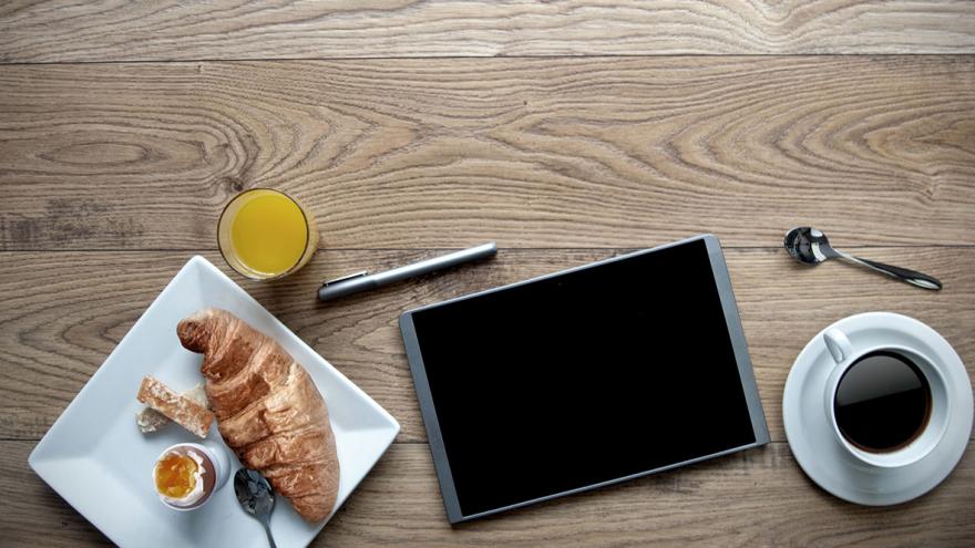Digitales Verbraucherpolitisches Frühstück: Teller mit Croissant und Frühstücksei, Kaffee, Orangensaft und ein Tablet-PC