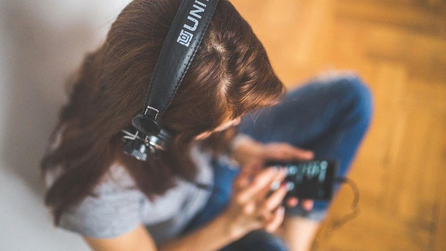 Eine junge Frau streamt über Kopfhörer Musik aus ihrem Smartphone 