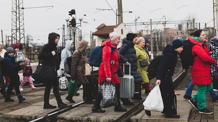 Eine Gruppe von Menschen in der Ukraine läuft mit Taschen über einen Gleisabschnitt