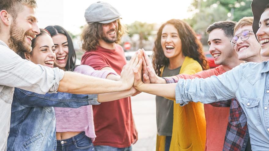 Eine Gruppe junger Menschen streckt die Arme gemeinsam in die Mitte zum Handschlag  