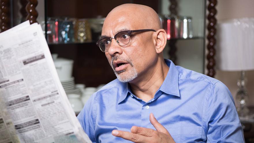 Ein Mann sitzt fassunglos mit einer aufgeschlagenen Zeitung in der Hand