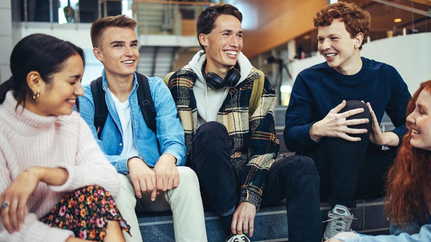 Eine Gruppe Jugendlicher sitzt auf einer Treppe in einer Schule