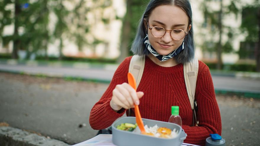 Eine junge Frau isst aus einer Lunchbox